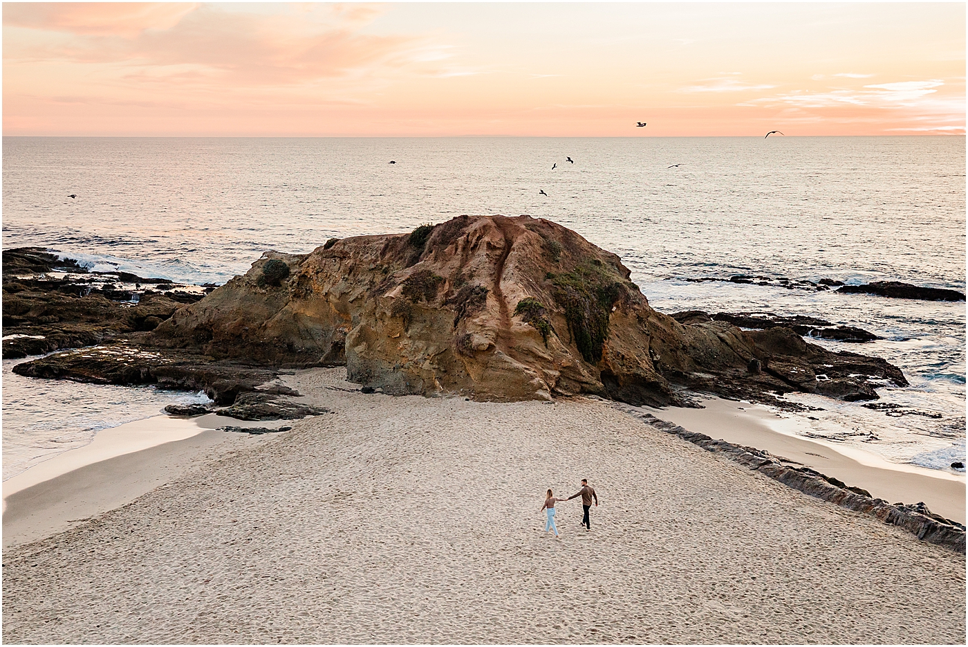 Laguna beach couples photography at Treasure Island Park. Guy and girl walking hand in hand on the beach during the sunset.