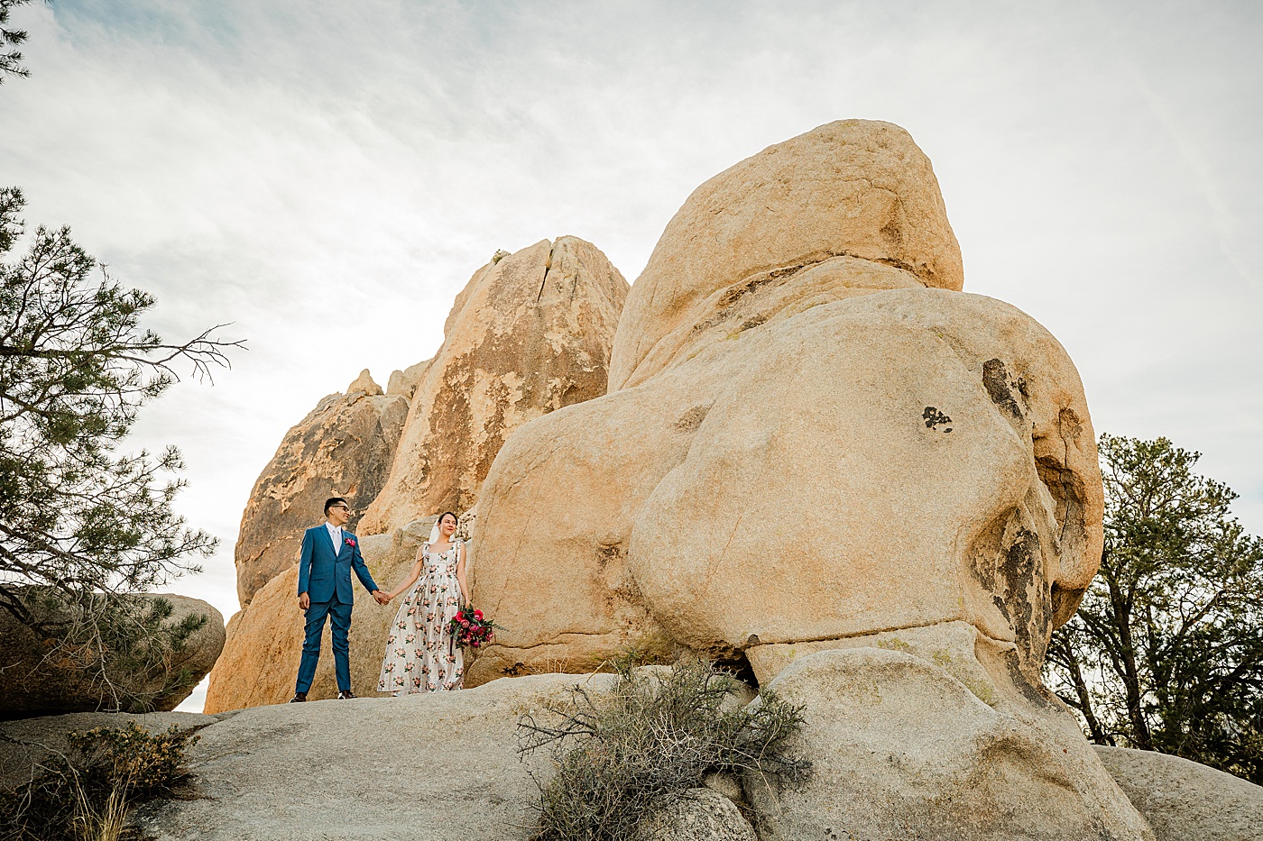 Joshua Tree elopement. Bride and groom holding hands on rock formation.