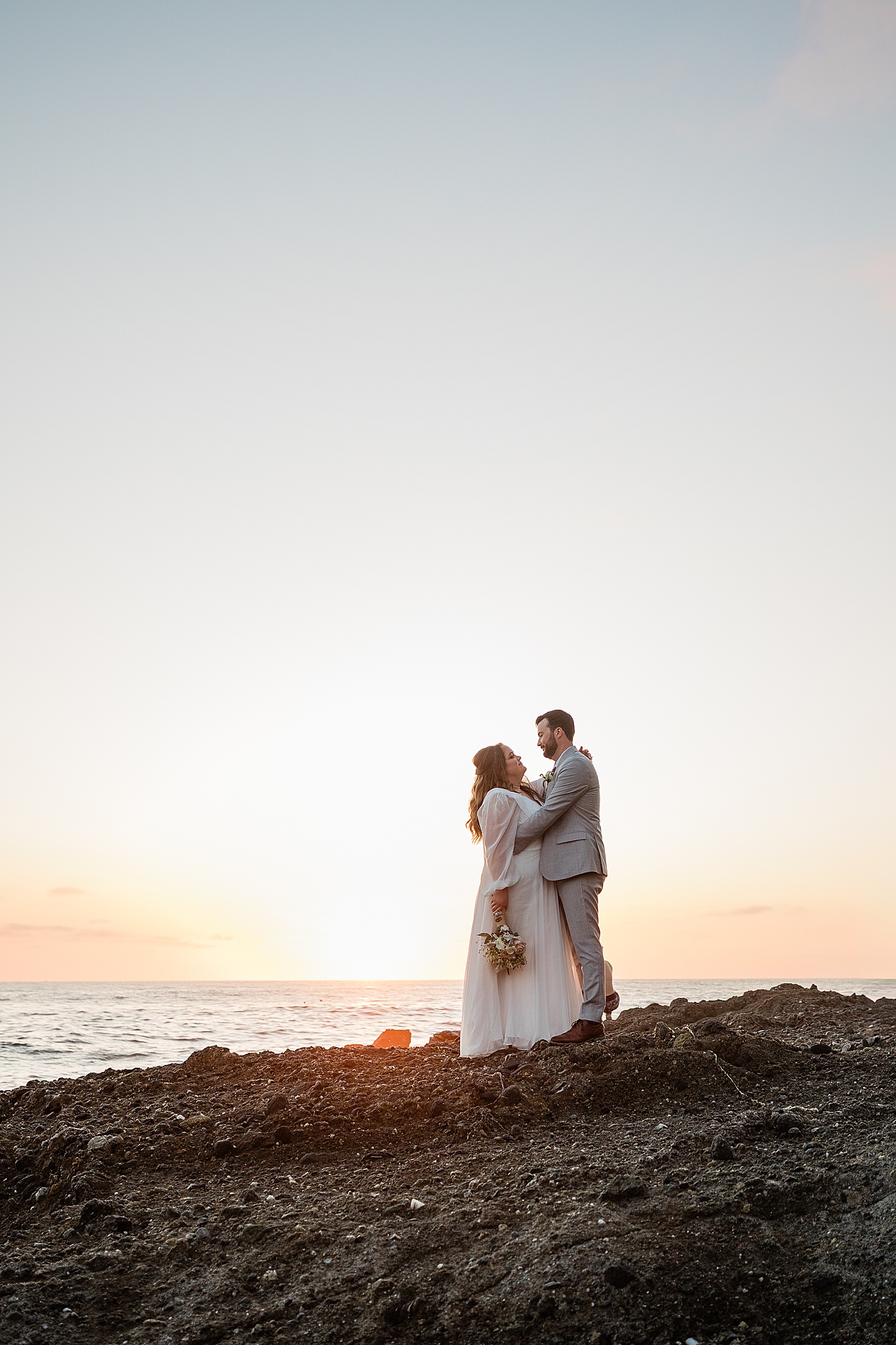 Bride and groom hug in front of the sunset in Orange County elopement.