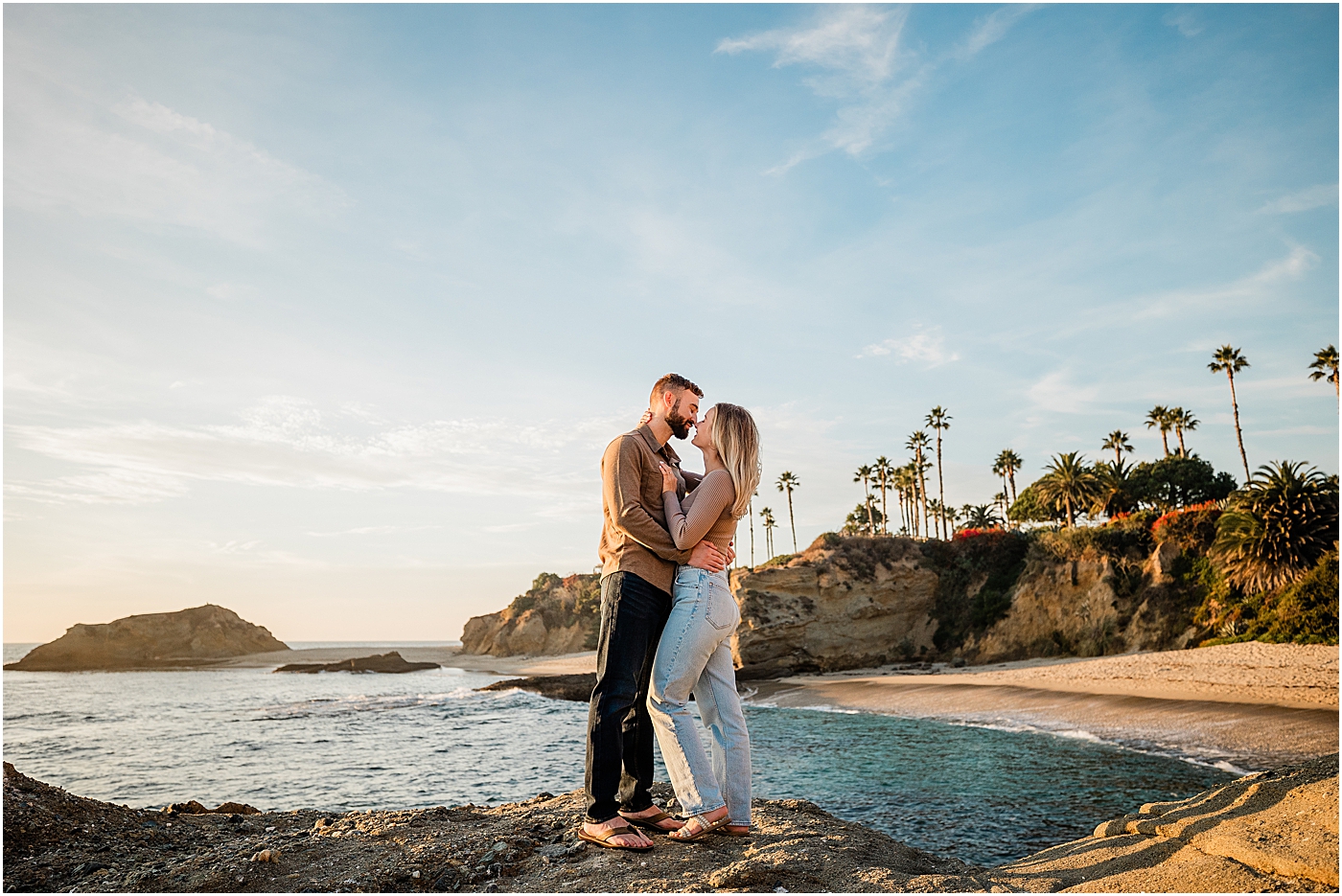 Laguna beach couples photography at Treasure Island Park. Couple standing on rocks in front of the ocean.
