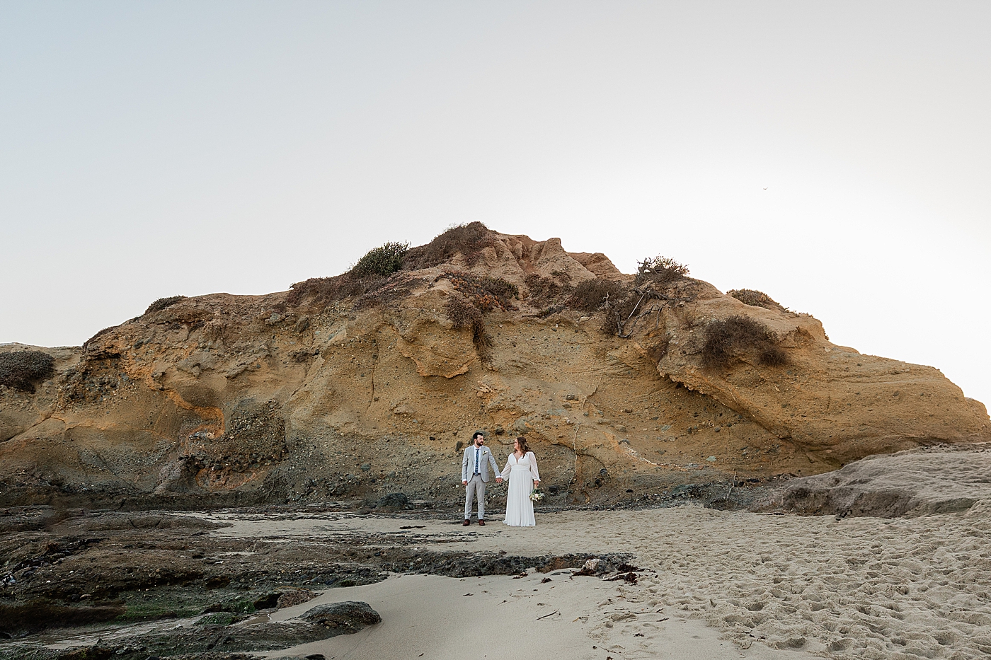 Bride and groom holding hands at the beach during Orange County Elopement.